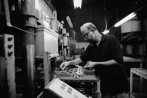 Black and white photograph of someone working at a printing press or typesetting machine.