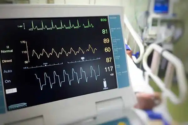 Medical vital signs monitor displaying multiple waveforms and numerical readings.